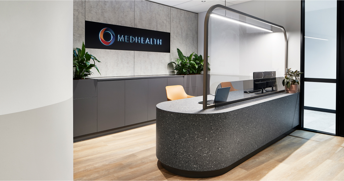 Modern office reception area with MedHealth logo on the wall designed by MOO Marketing & Design's graphic designers in Melbourne