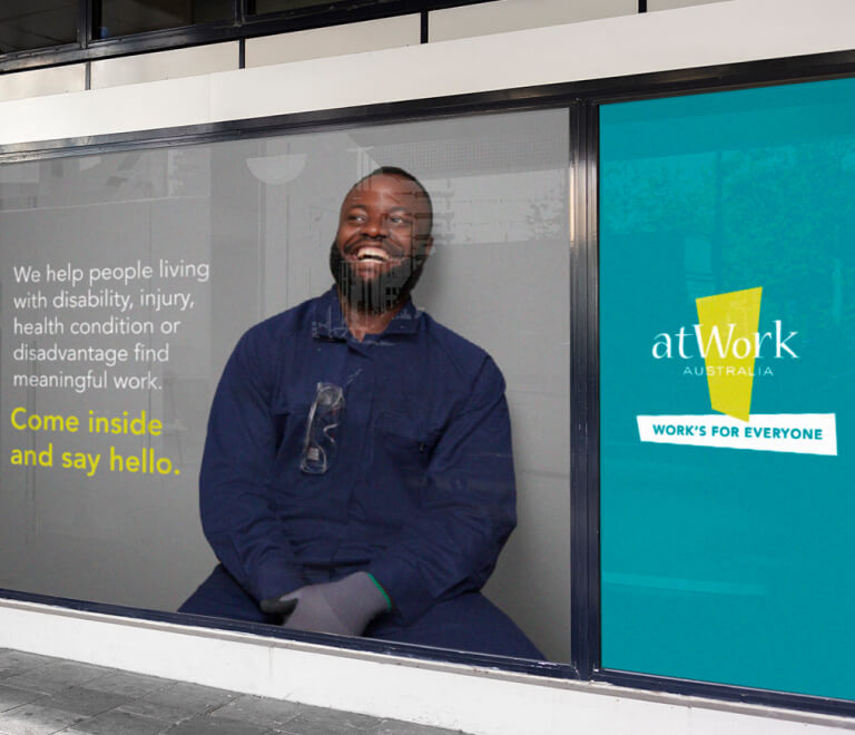 Bus station ad for atWork Australia featuring smiling man next to block quote, designed by MOO Marketing & Design