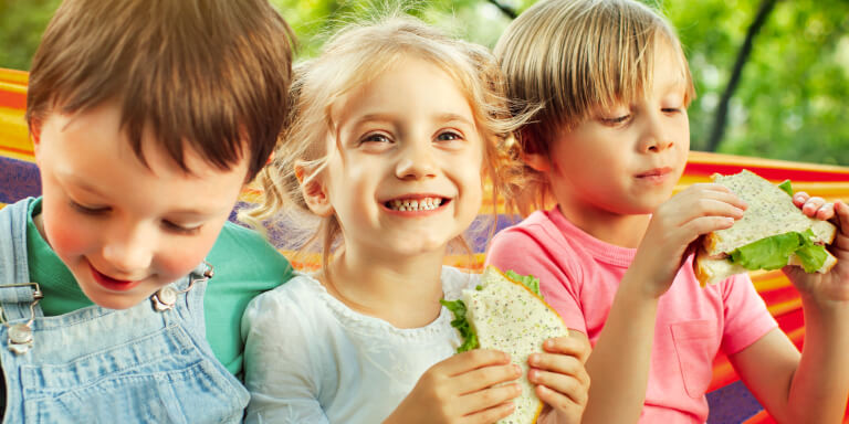 Advertisement featuring three smiling children eating bread designed by MOO Marketing & Design graphic design team
